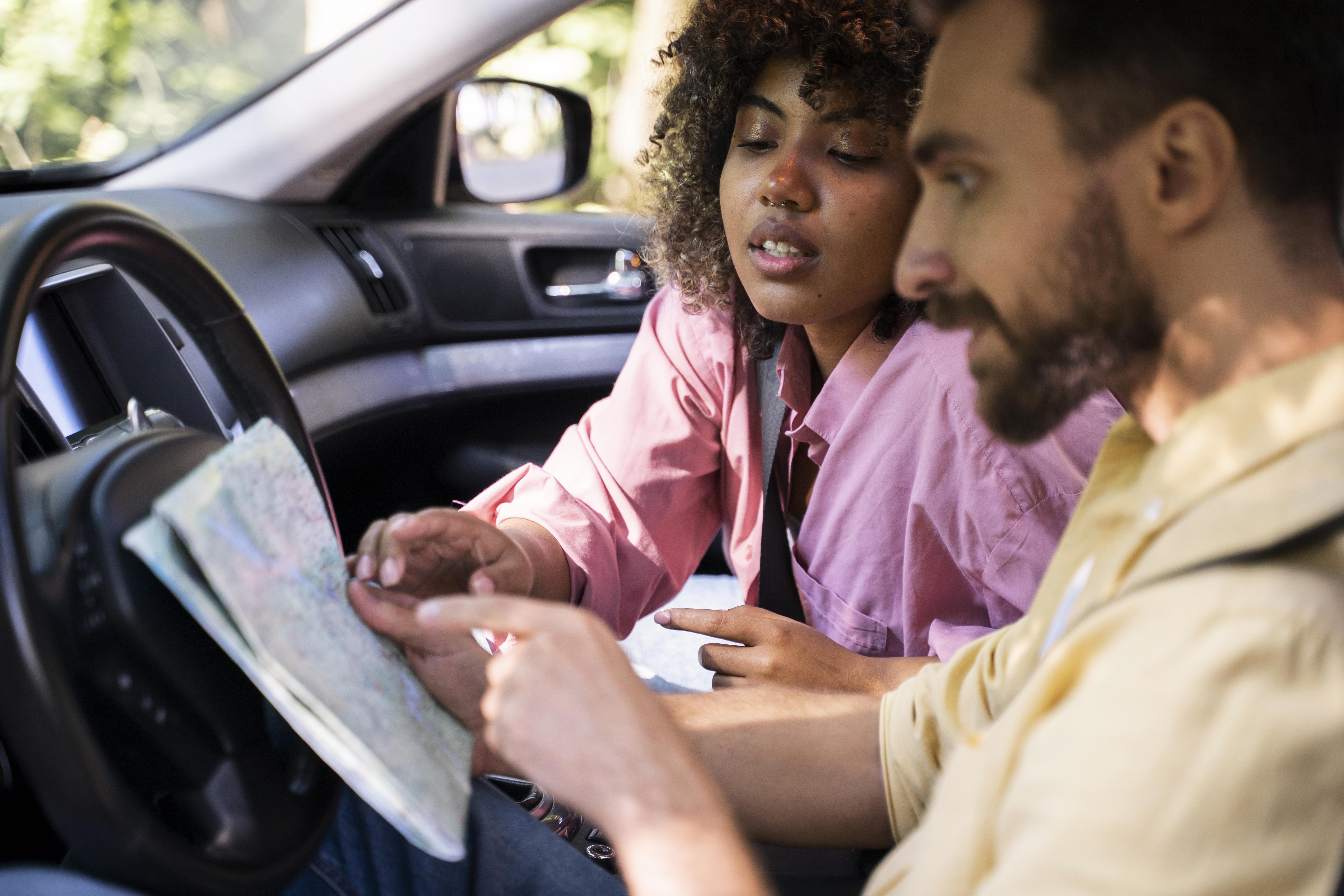 An instructor helping a learner plan a route inside a car